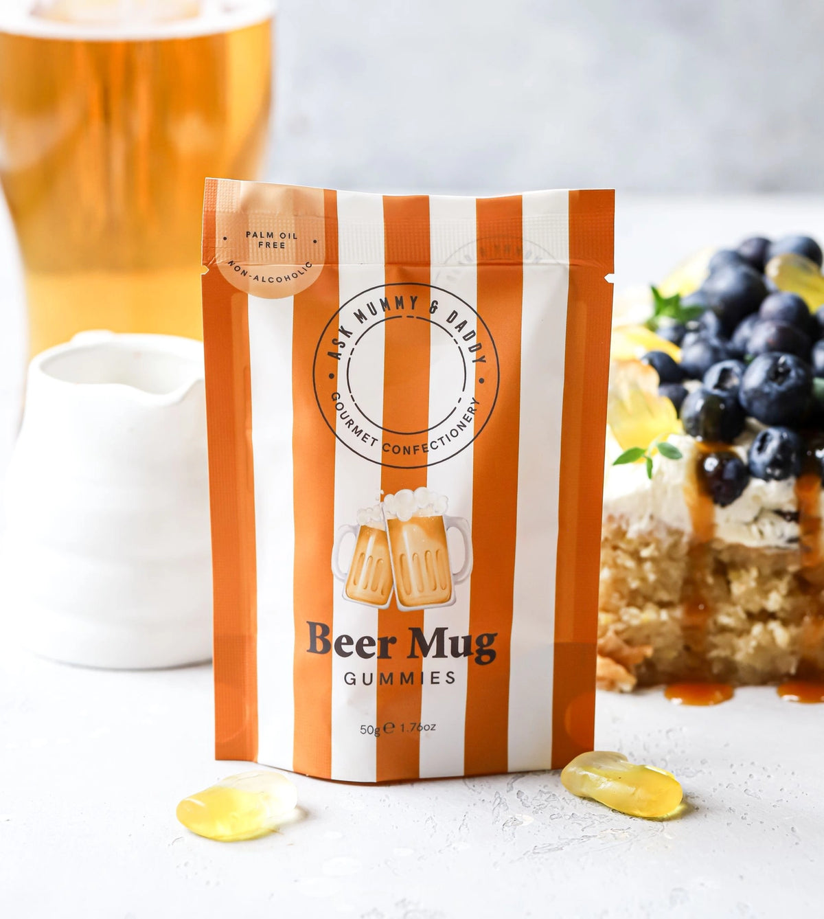 Package of 'Beer Mug' gummies with a glass of beer and dessert in the background