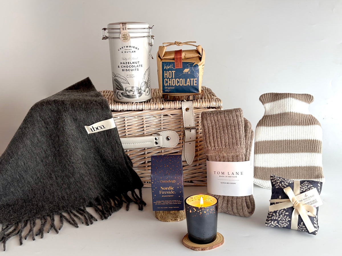 Cosy Hamper with hot water bottle, scarf, cosy alpaca bed socks, candle, hot chocolate, biscuit tin and microwaveable handwarmer in a white wicker hamper basket