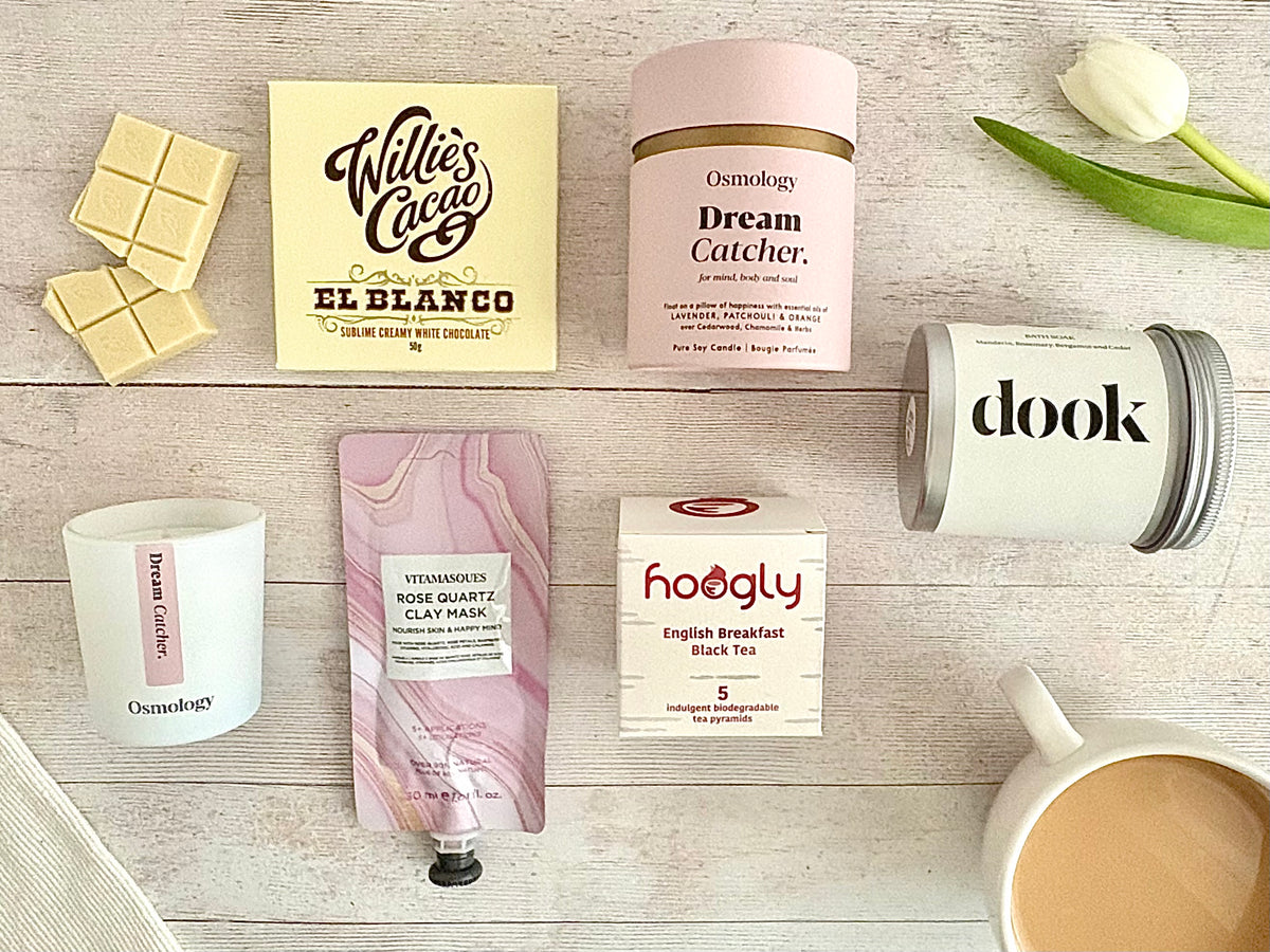 Bath salts, candle, white chocolate, english breakfast tea, clay face mask on wooden background with tulip and cup of tea