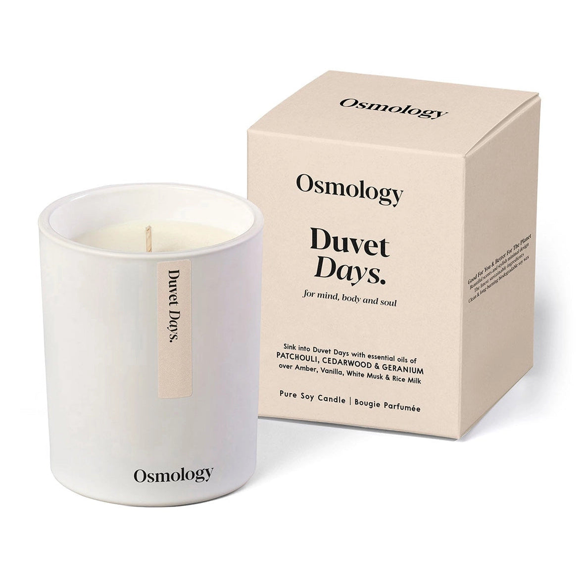 An Osmology candle in a white glass jar next to its beige cardboard packaging box, labeled 'Duvet Days'.