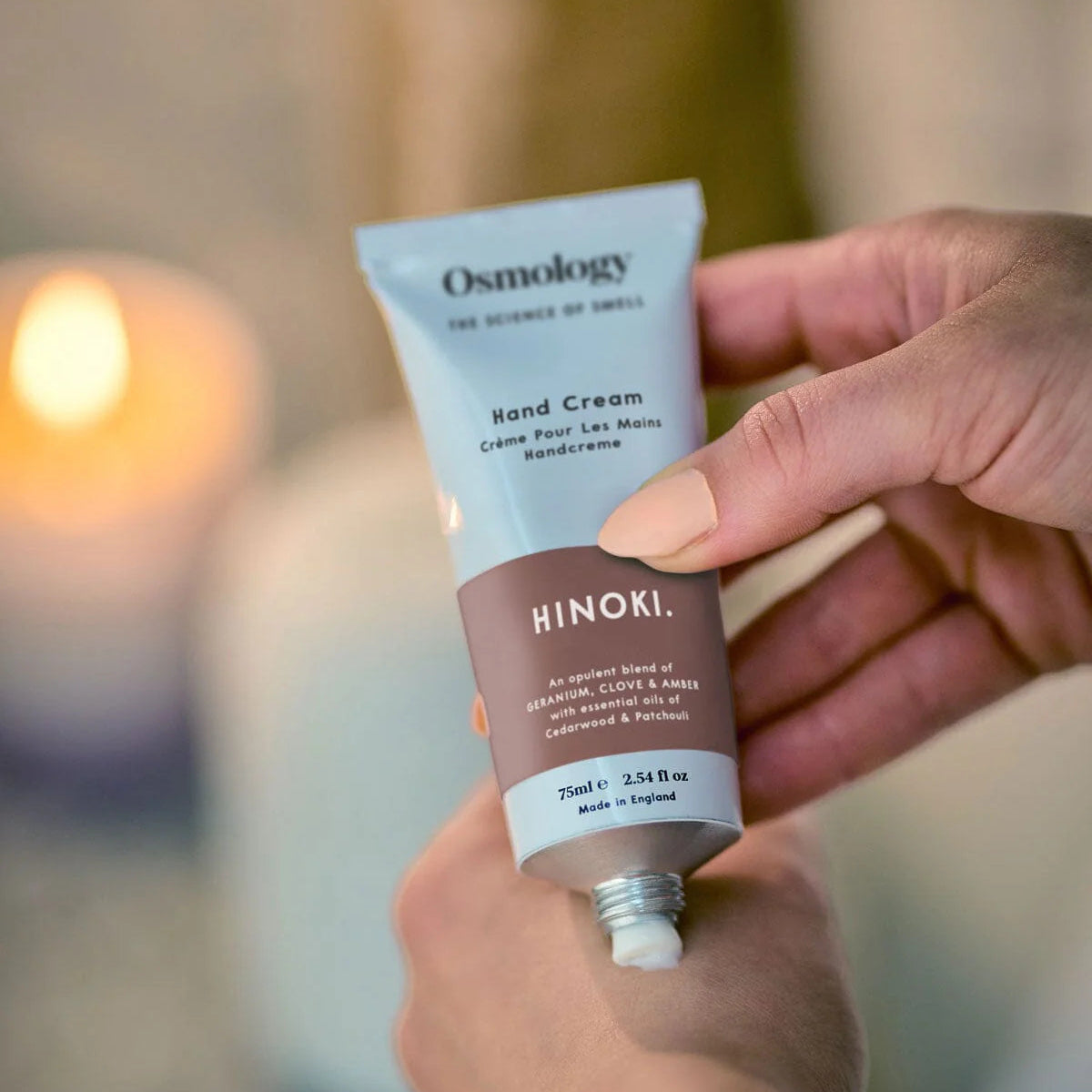 Osmology Hinoki hand cream and packaging on a brown background