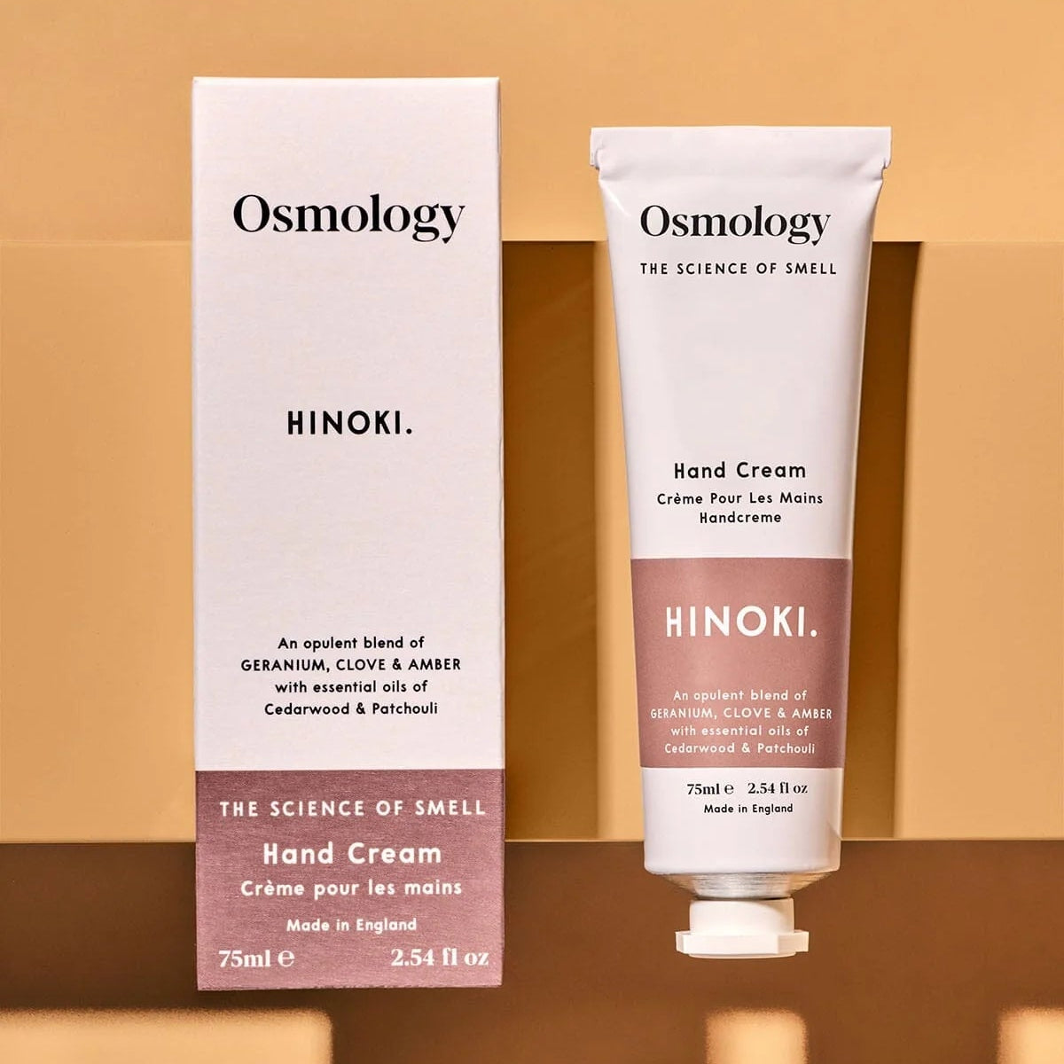 Osmology Hinoki hand cream and packaging on a brown background