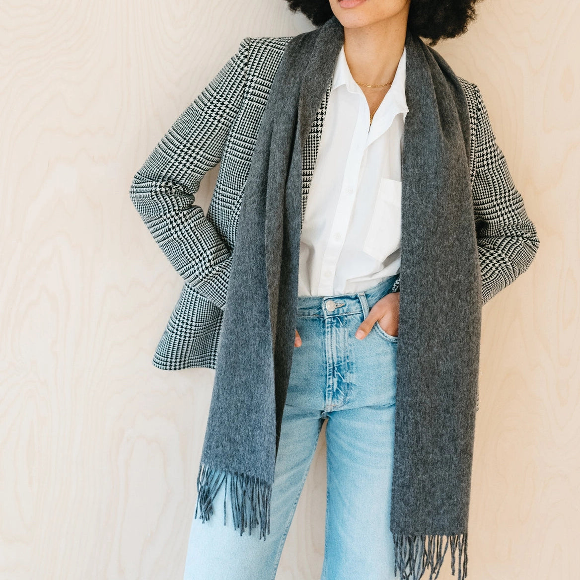 Charcoal Grey 100% lambswool scarf with fringe on wooden rod against a neutral, warm off-white background.