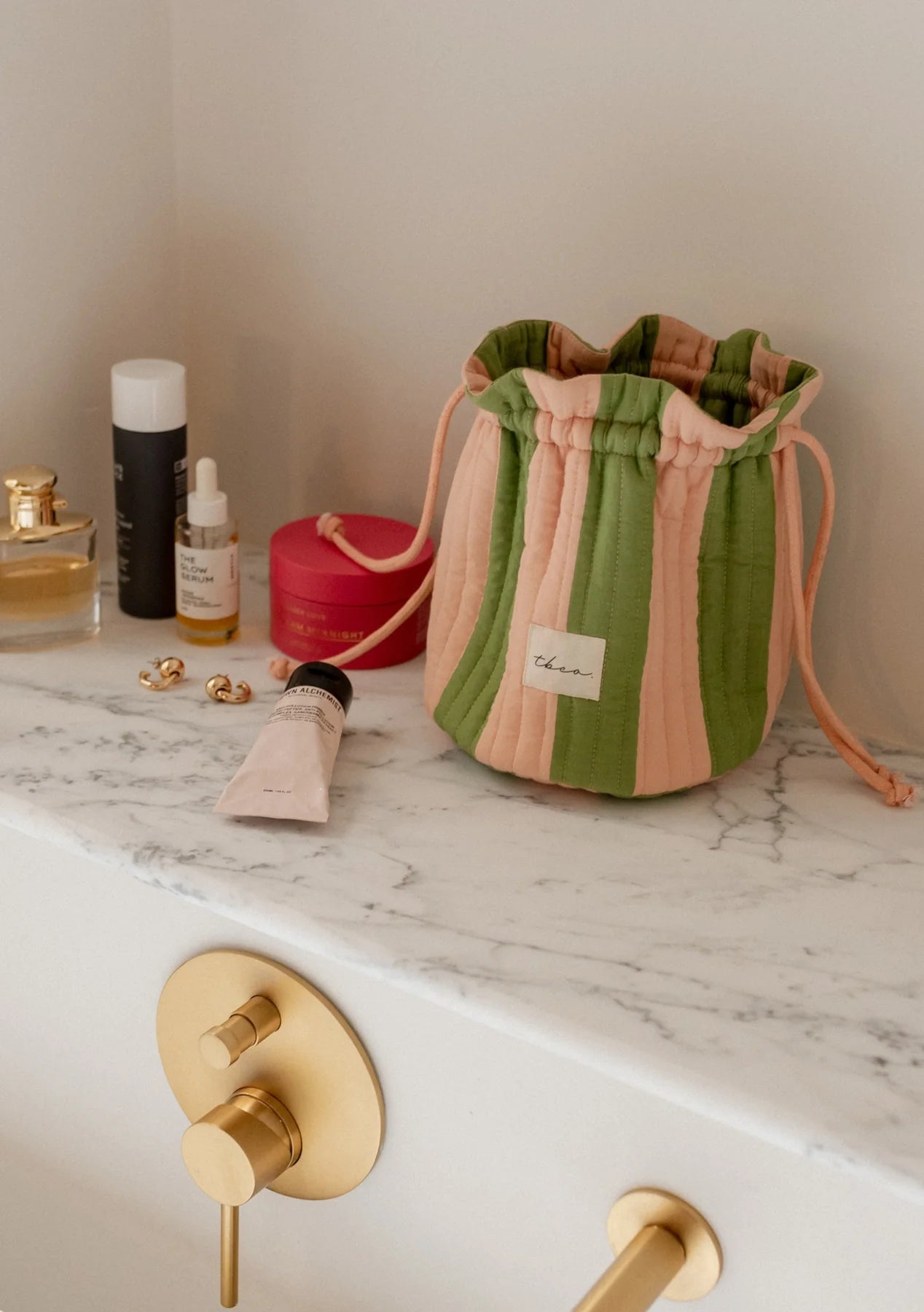 Drawstring bag with pink and green stripes on a beige background