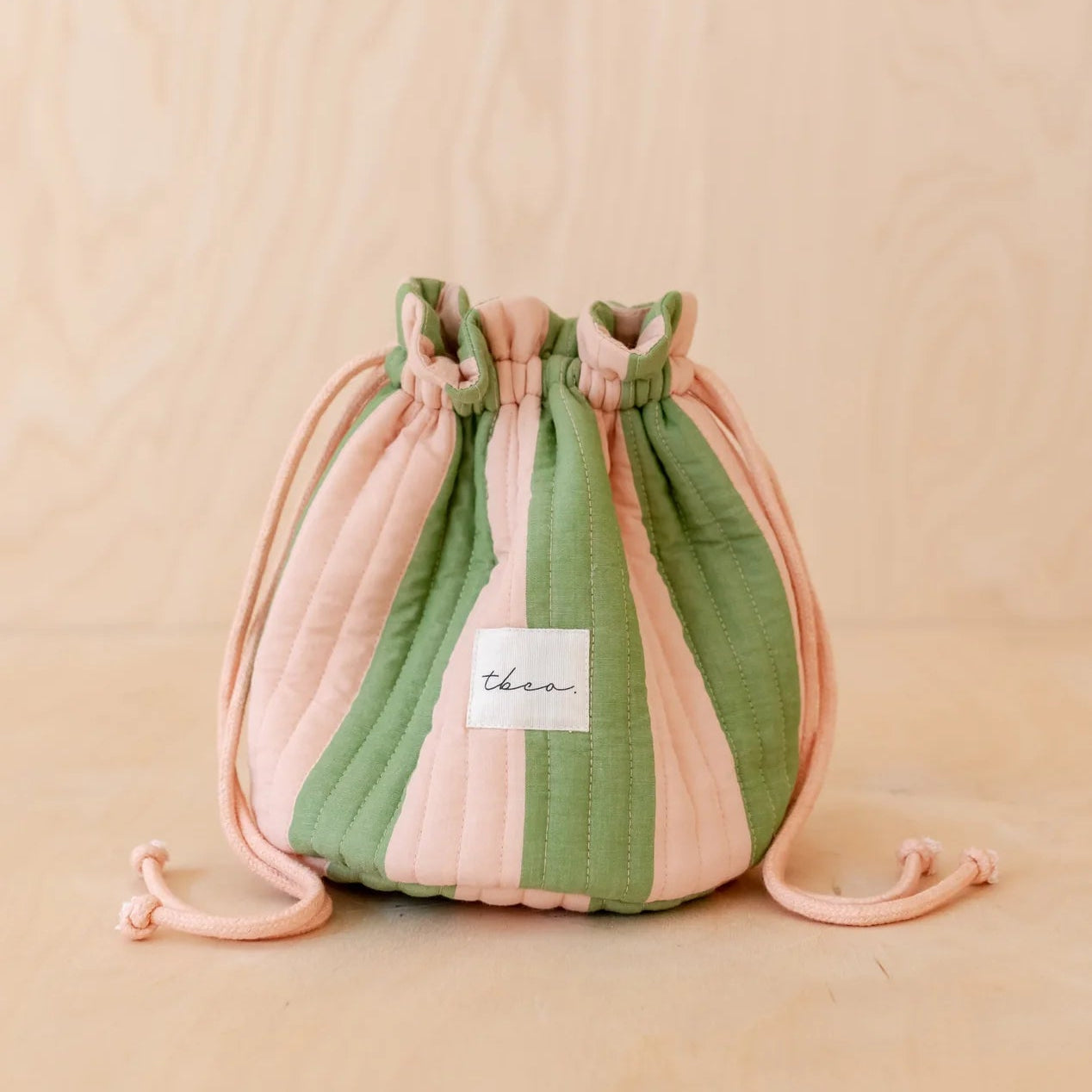 Drawstring bag with pink and green stripes on a beige background